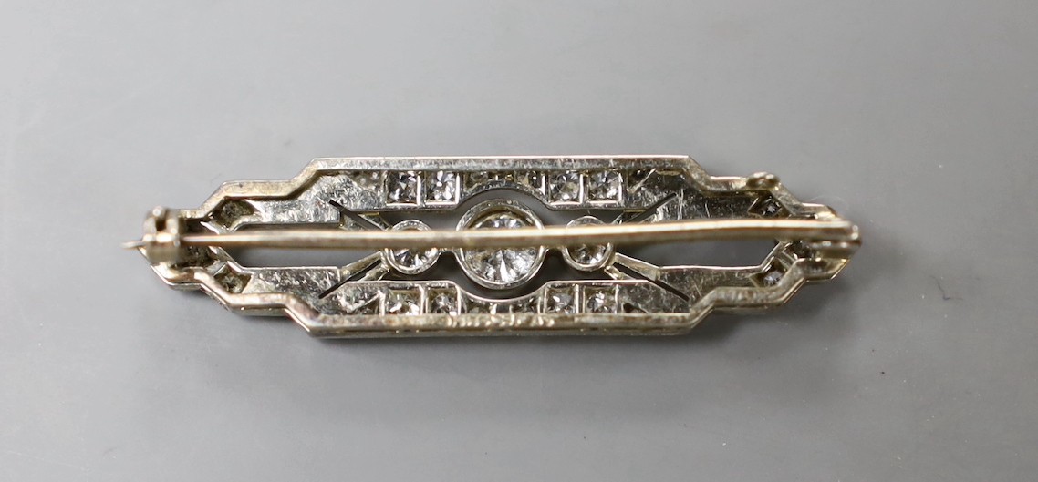 An Art Deco 18ct, plat and diamond cluster shaped bar brooch, with millegrain set stones, 37mm, gross weight 4.7 grams.